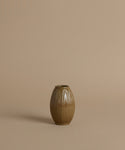 A ribbed ceramic vases with a glossy brown glaze, arranged against a solid beige background.