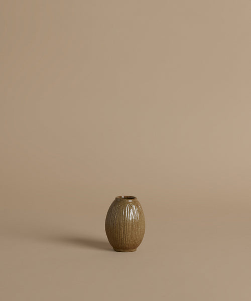A ribbed ceramic vases with a glossy brown glaze, arranged against a solid beige background.