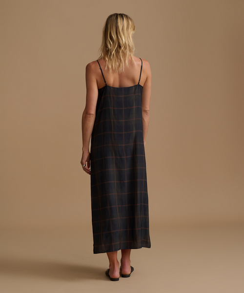 Woman wearing a plaid dress against a beige studio background.