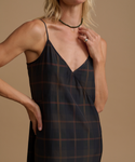 Woman wearing a plaid dress against a beige studio background.