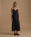 Woman wearing a plaid dress against a beige studio background.