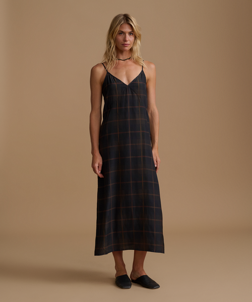 Woman wearing a plaid dress against a beige studio background.