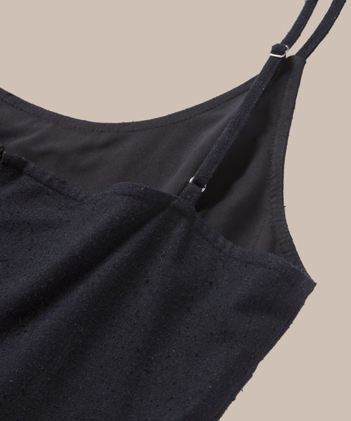 Close-up of the Rove Dress top, a black sleeveless spring-summer dress with thin adjustable straps, textured fabric, and smooth lining, set against a beige background.