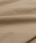 Close-up of the light brown cotton fabric on the Rove Dress, with soft folds and subtle texture that emphasize its detailed weave and surface.