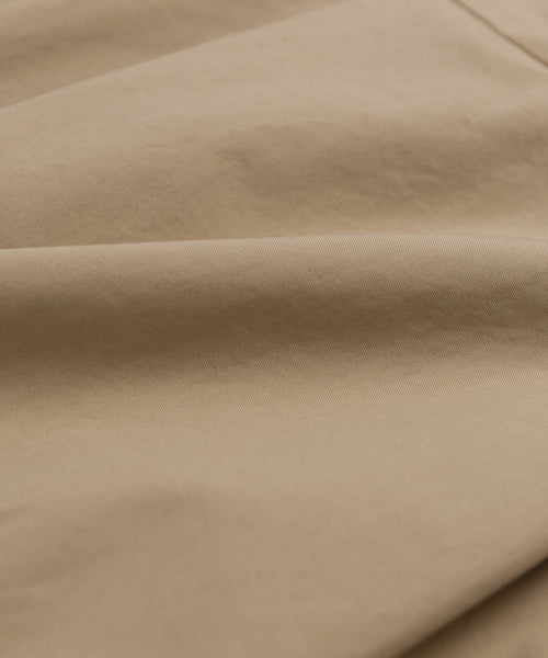 Close-up of the light brown cotton fabric on the Rove Dress, with soft folds and subtle texture that emphasize its detailed weave and surface.