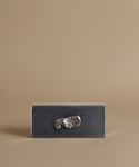 A rectangular dark charcoal gray box with a polished silver metallic scrollwork handle, set against a solid warm beige background.