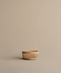The Seagrass Produce Bowl is a small, empty bowl on a light brown surface with a beige background, ideal for kitchen storage or displaying fresh fruit.