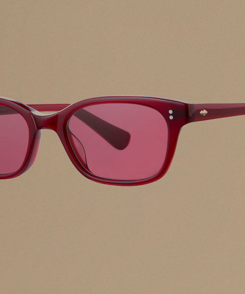 Red sunglasses against a beige background.