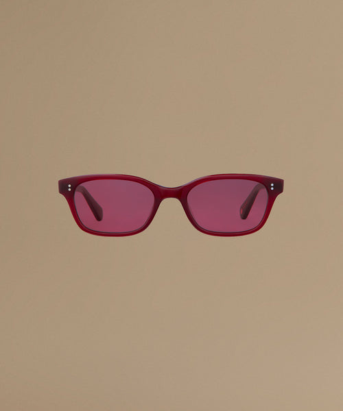 Red sunglasses against a beige background.