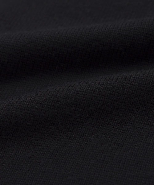 Close-up of the Simone V-Neck in black, showing its textured cotton merino fabric with visible weave and soft folds, highlighting a smooth and flexible everyday layer.