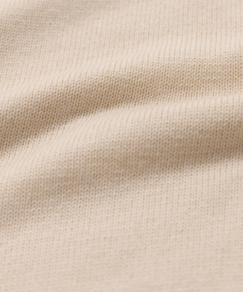 Close-up of the Simone V-Neck in beige, featuring a detailed cotton merino knit with visible texture and soft, wavy folds. Even stitches highlight the luxury quality of this fine layer.