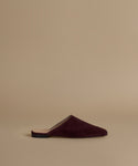 A single deep burgundy suede mule slipper shown in profile against a solid beige background.