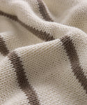 A close-up of the Chloe Crewneck, a soft cream-colored Peruvian cotton sweater featuring horizontal brown stripes and a subtly wavy texture.