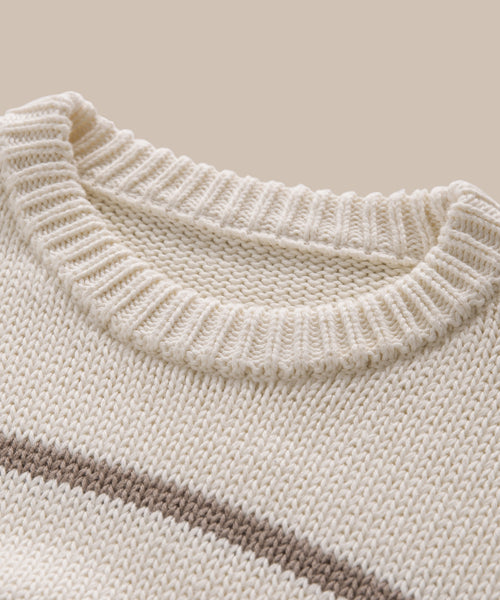 Close-up of the Chloe Crewneck’s neckline, featuring cream-colored Peruvian cotton with a ribbed collar and a subtle horizontal brown stripe across the chest, set against a beige background.