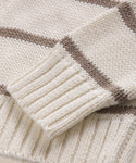 Close-up of the Chloe Crewneck, a cream-colored sweater with brown horizontal stripes. The ribbed cuff and hem highlight the detailed stitching and texture of Peruvian cotton yarn.