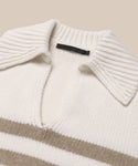 A close-up of the cream-colored Cashmere Phoebe Polo sweater, featuring a wide ribbed collar, V-neckline, and horizontal beige stripes across the chest, laid flat on a neutral background.