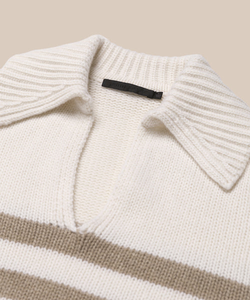 A close-up of the cream-colored Cashmere Phoebe Polo sweater, featuring a wide ribbed collar, V-neckline, and horizontal beige stripes across the chest, laid flat on a neutral background.