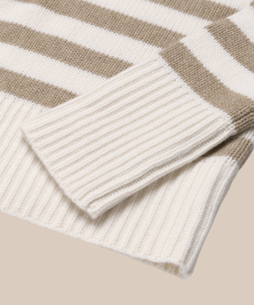 A close-up of the Cashmere Phoebe Polo shows its knitted sleeve and hem with wide ivory and beige stripes, complemented by ribbed cuffs and bottom edge for an elegant finish.