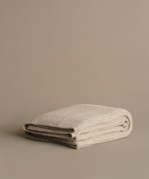 The Wool Fisherman Throw, crafted in Peru from premium Andean Highland wool, is folded and displayed on a neutral taupe surface with a coordinating background.
