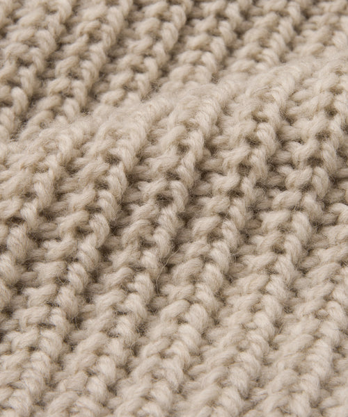 Close-up of the Wool Fisherman Throw, showcasing its beige chunky ribbed knit in soft Andean Highland wool. Thick, raised rows emphasize the cozy warmth of this Peruvian-made throw.