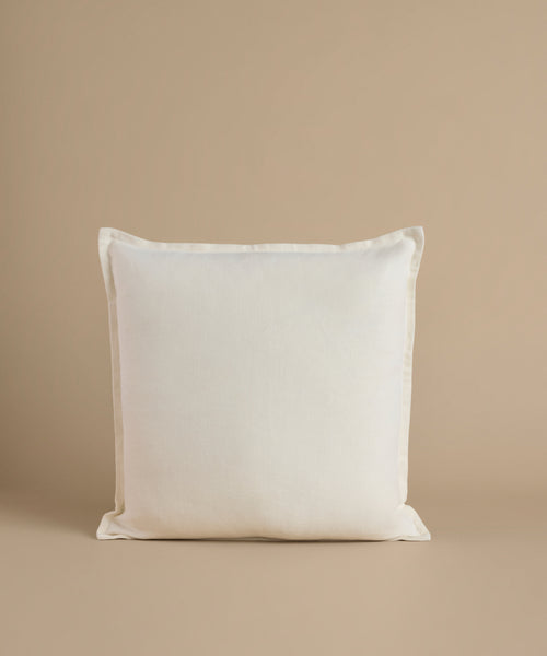 A white square pillow against a beige background.