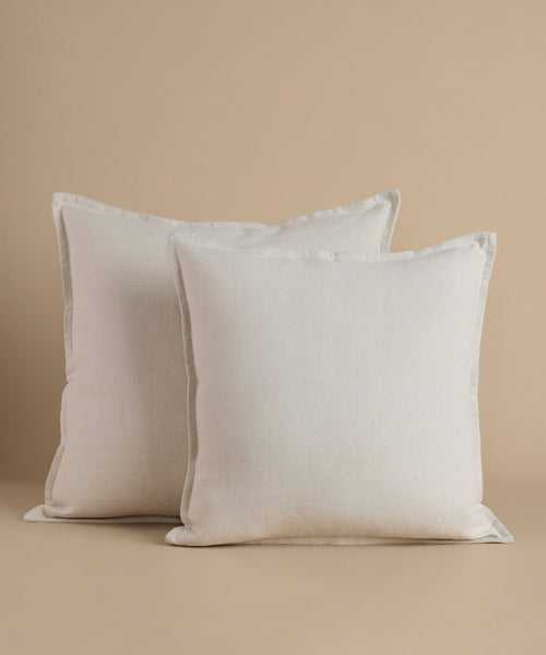 Cream square pillows against a beige background.