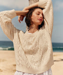 Woman wearing a cream cable knit sweater on a beach