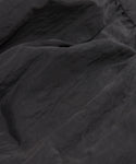 Close-up of dark gray, slightly wrinkled textured fabric with soft folds and a subtle sheen, featured in the Alyssandra Dress—its smooth, lightweight material is perfect for an elegant party look.