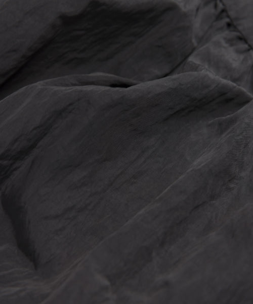 Close-up of dark gray, slightly wrinkled textured fabric with soft folds and a subtle sheen, featured in the Alyssandra Dress—its smooth, lightweight material is perfect for an elegant party look.