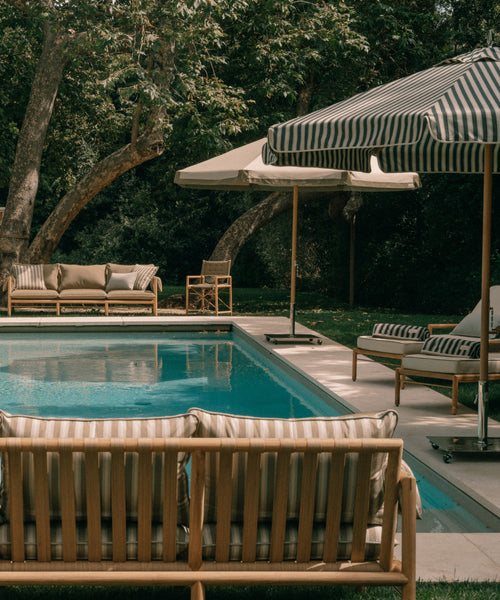 Outdoor seating area with striped umbrellas and couches by a pool