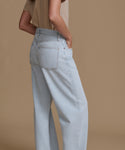 Light blue jeans worn by a person on a brown background