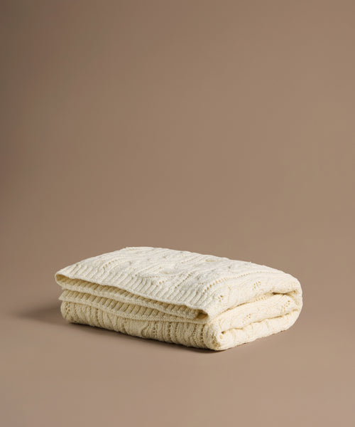 Folded beige textured blanket on a brown background