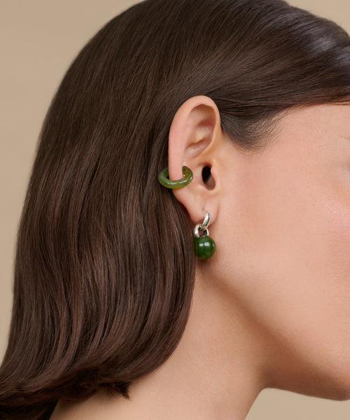 A close-up of a womans ear showcases the Bagel Ear Cuff paired with a round drop earring, complementing her straight brown hair and light skin in an elegant, Sophie Buhai-inspired style.