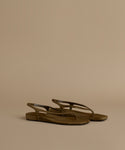 Pair of olive sandals on a beige background