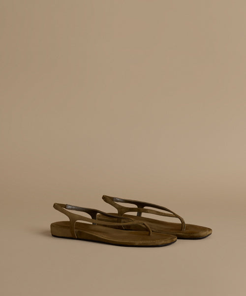 Pair of olive sandals on a beige background