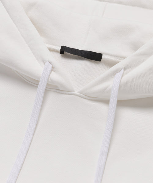 Close-up of the Bay Hoodie highlights its hood, drawstrings, and a black tag at the neckline. The soft, slightly textured fabric makes it a cozy addition to your wardrobe.