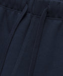 Close-up of the Bay Sweatpant, featuring a navy blue brushed fleece fabric. The image highlights the waistband, drawstrings, visible stitching details, and the textured feel of these athletic sweats.