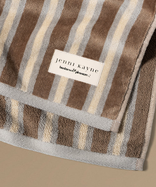 Folded striped towel with a brand label on a beige background