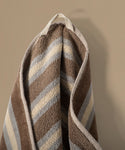 Striped towel with brown, beige, and blue pattern on a beige background