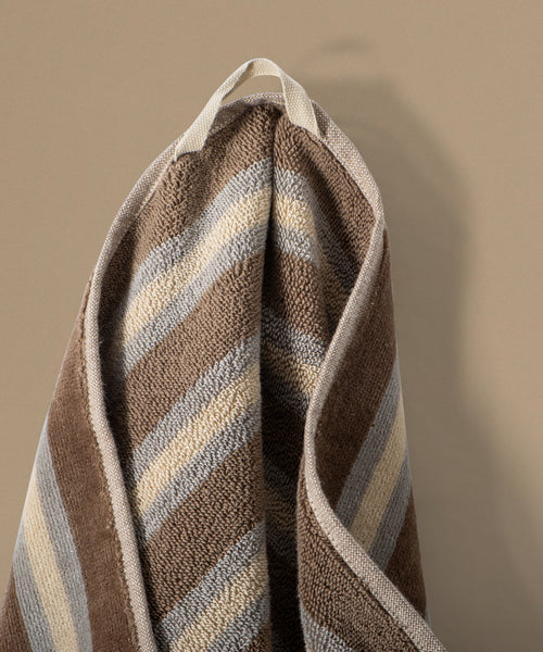 Striped towel with brown, beige, and blue pattern on a beige background