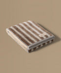 Folded striped towel with a brand label on a beige background