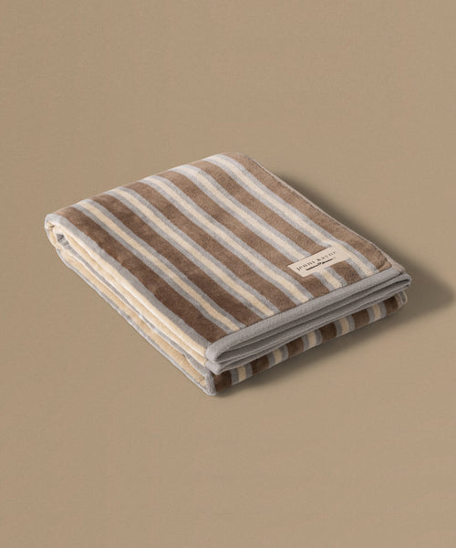 Folded striped towel with a brand label on a beige background