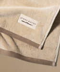 Beige towel with 'jenni kayne' label on a beige background
