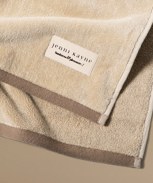 Beige towel with 'jenni kayne' label on a beige background