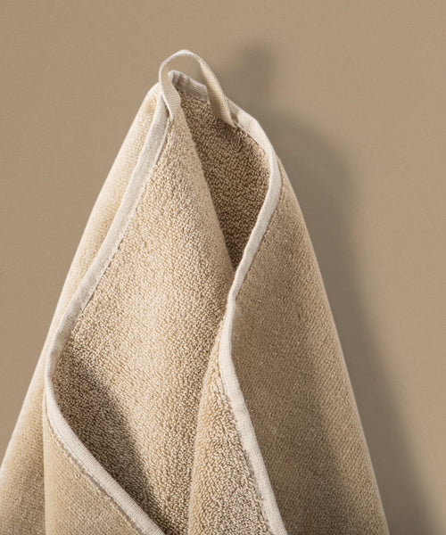 Beige towel hanging against a beige background