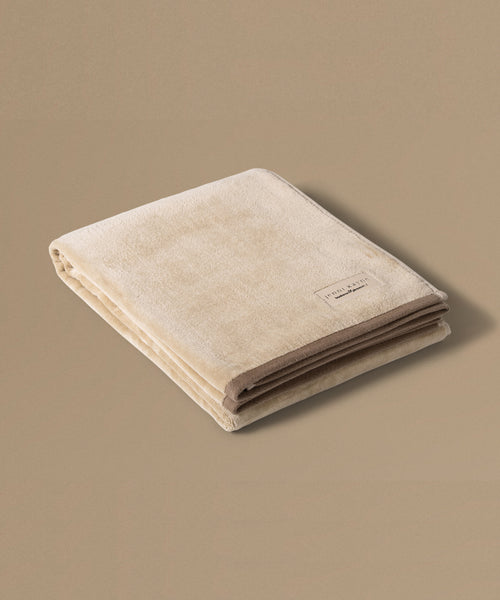 Folded beige towel with a brand label on a beige background