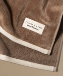 Brown towel with 'jenni kayne' label on a beige background