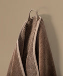 Brown towel hanging against a beige wall