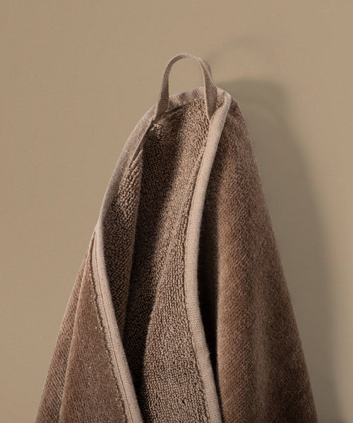 Brown towel hanging against a beige wall
