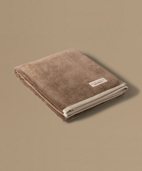 Brown towel with a brand label on a beige background
